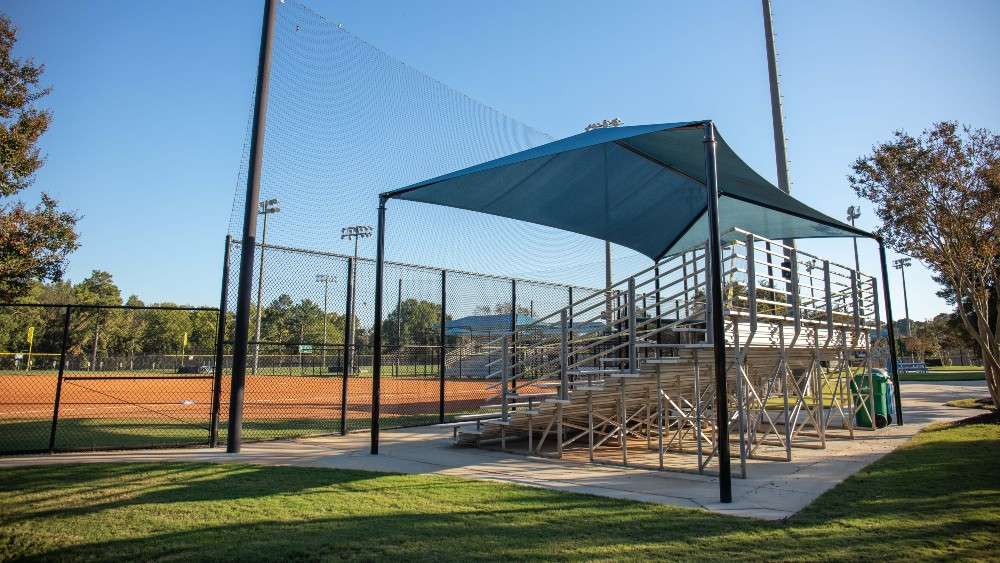 Shade sail covered aluminum bleachers by baseball field