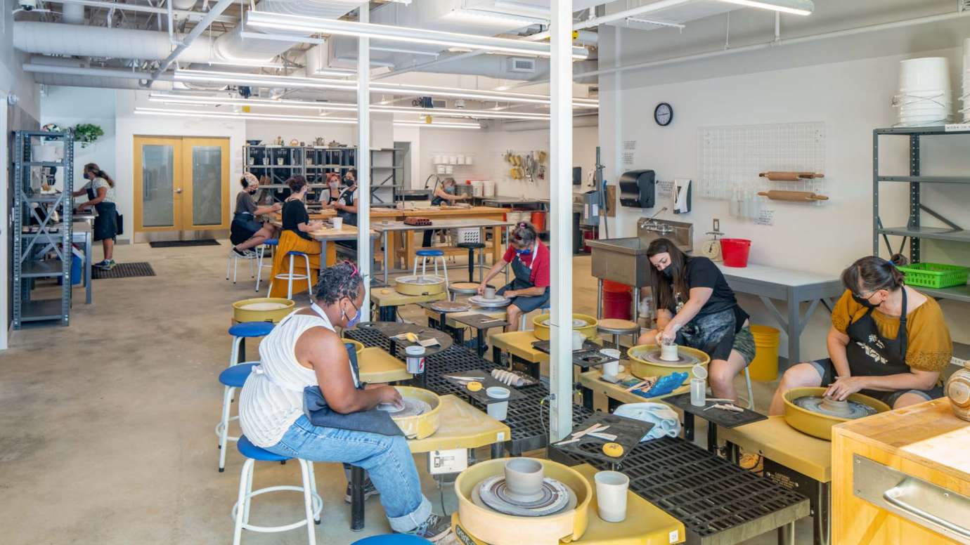 People sit and create at the pottery wheels in the Community Pottery Studio at Pullen Arts Center