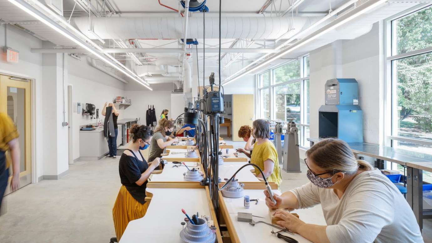 People working at tables with tools in the jewelry studio at Pullen Arts Center