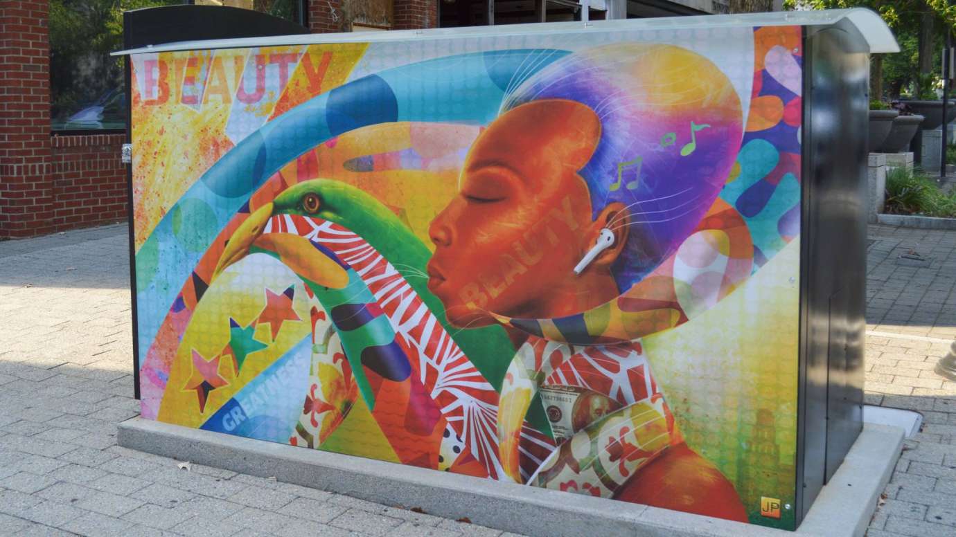 Artwork on a news rack kiosk that features a collage of a woman's face with color lines and the words Beauty and Greatness