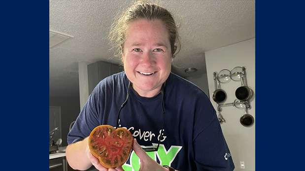 Woman holds tomato up in hands sliced in half