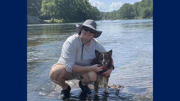 Woman with dog in river smiling