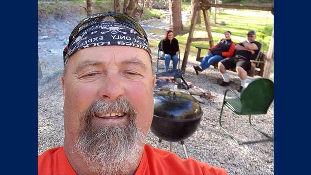 Man smiling in selfie with people in background