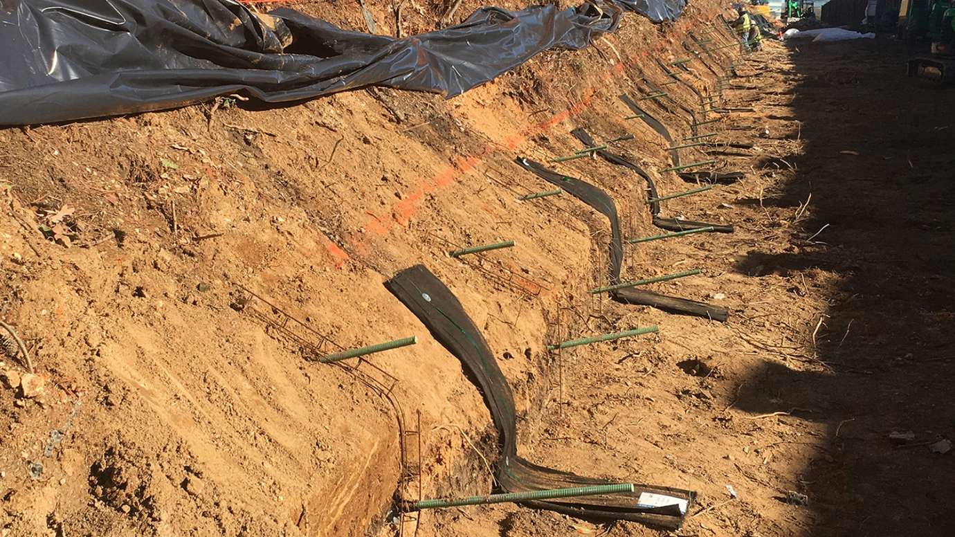 Inside the soil nail drill holes, reinforcing steel bars with centralizers are placed and then grout