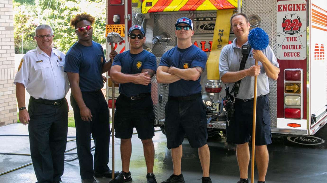 Firefighters standing behind fire truck