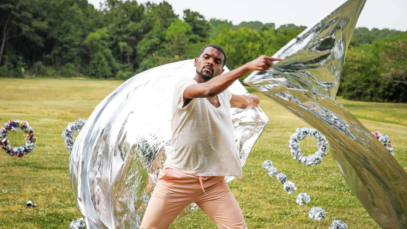 A man moves around while holding silver, reflective fabric