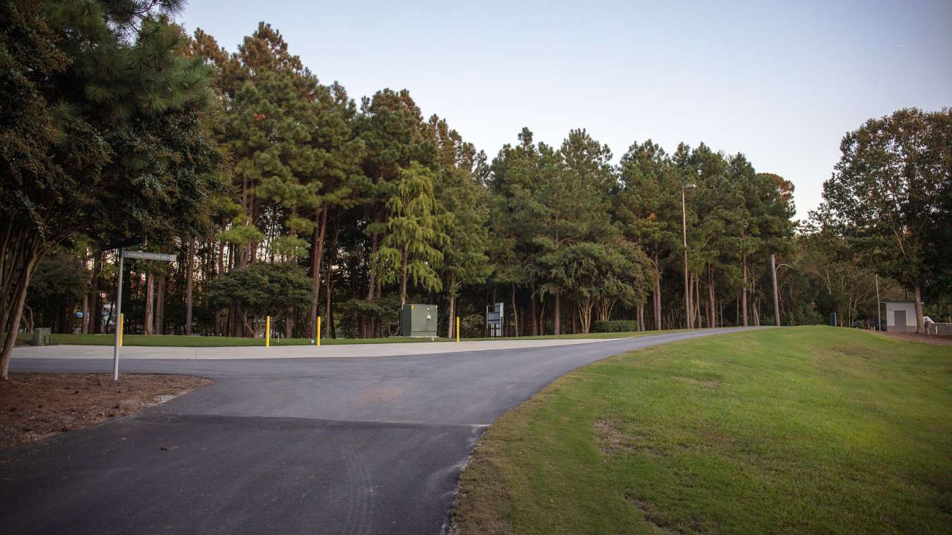 paved driveway surrounded by grass and trees 