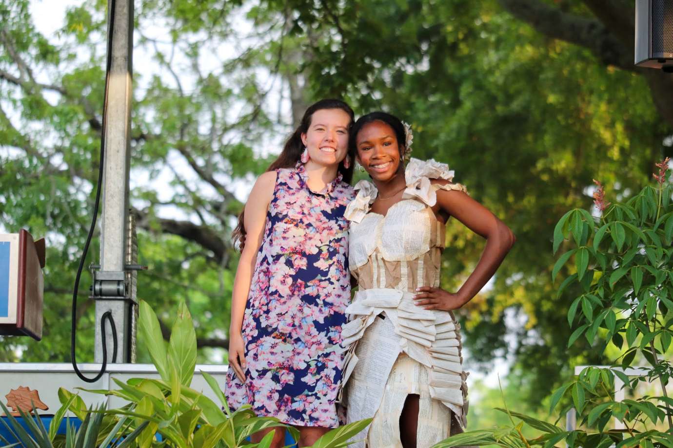 Two girls pose with the winning outfit on one of the girls. Outfit is made with pages from a book.