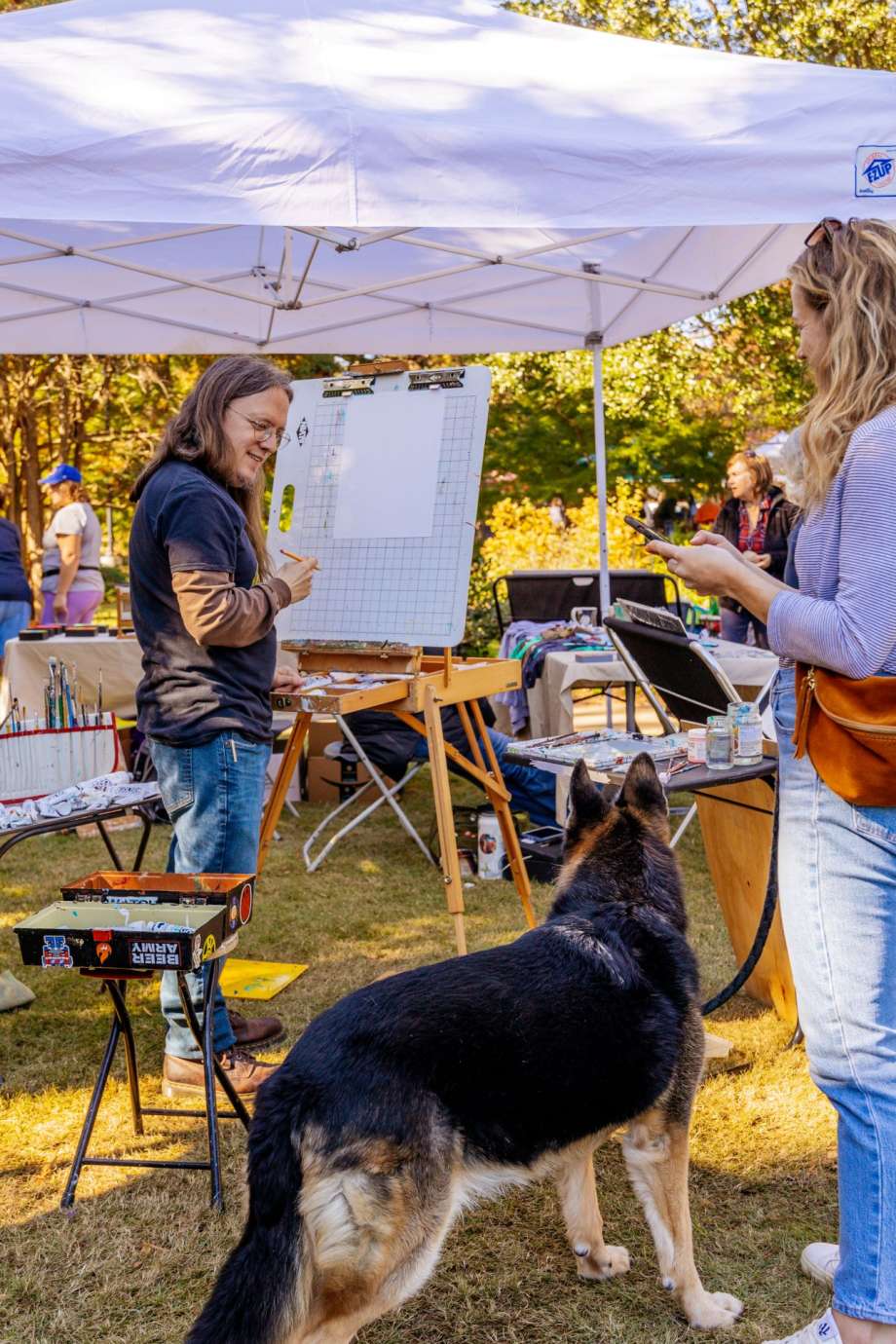 An adorable dog at a outdoor arts festival on a sunny day. 