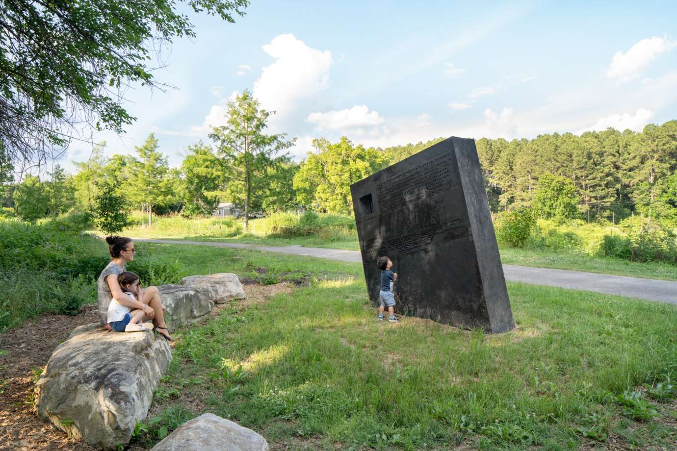 Image of a large concrete monolith sculpture with information about stormwater infrastructure printed on it.