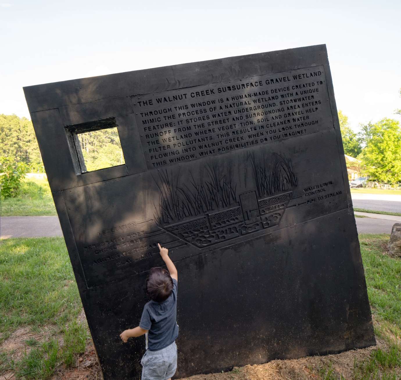 Image of a large concrete monolith sculpture with information about stormwater infrastructure printed on it.