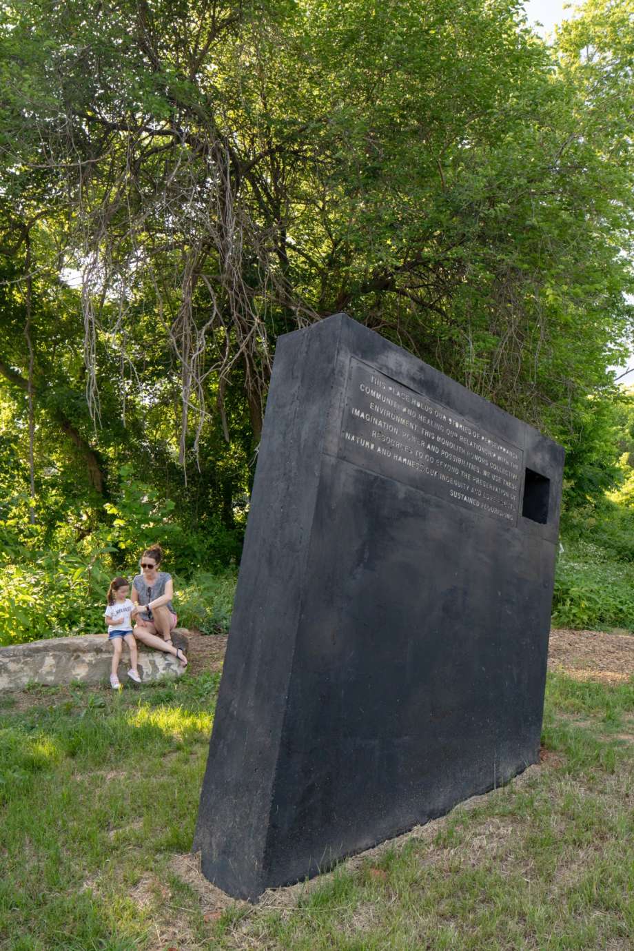 Image of a large concrete monolith sculpture with information about stormwater infrastructure printed on it.