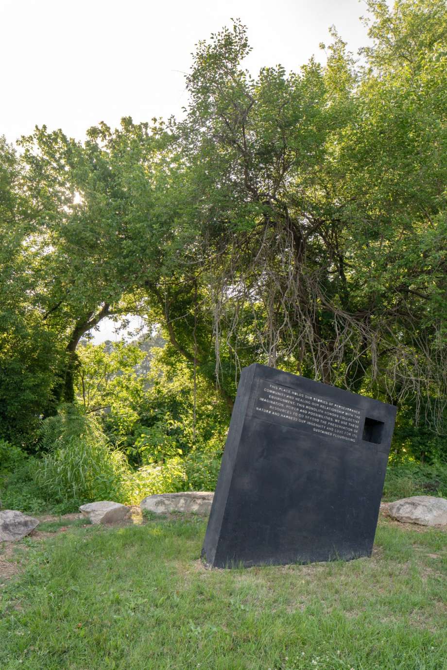 Image of a large concrete monolith sculpture with information about stormwater infrastructure printed on it.