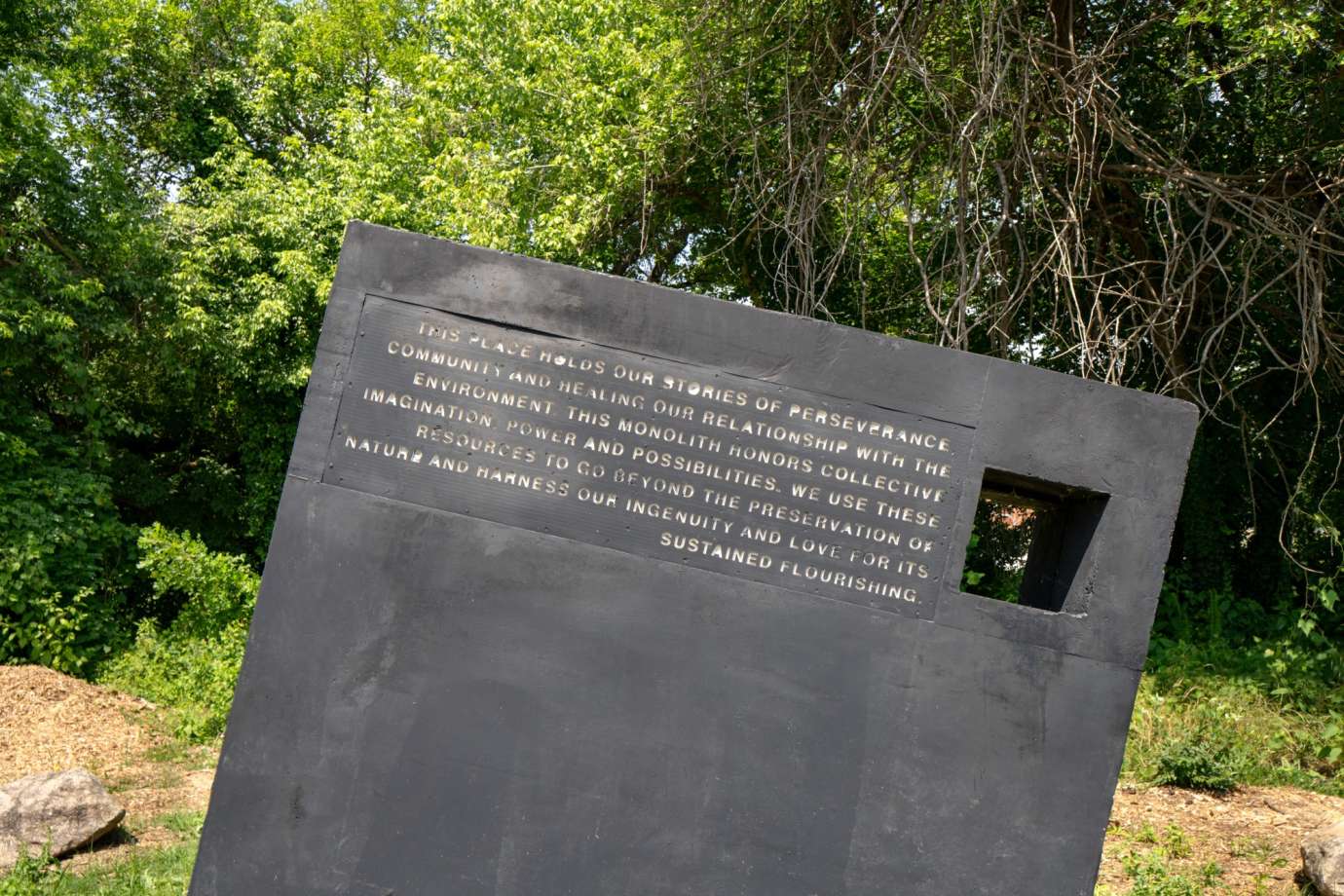 Image of a large concrete monolith sculpture with information about stormwater infrastructure printed on it.