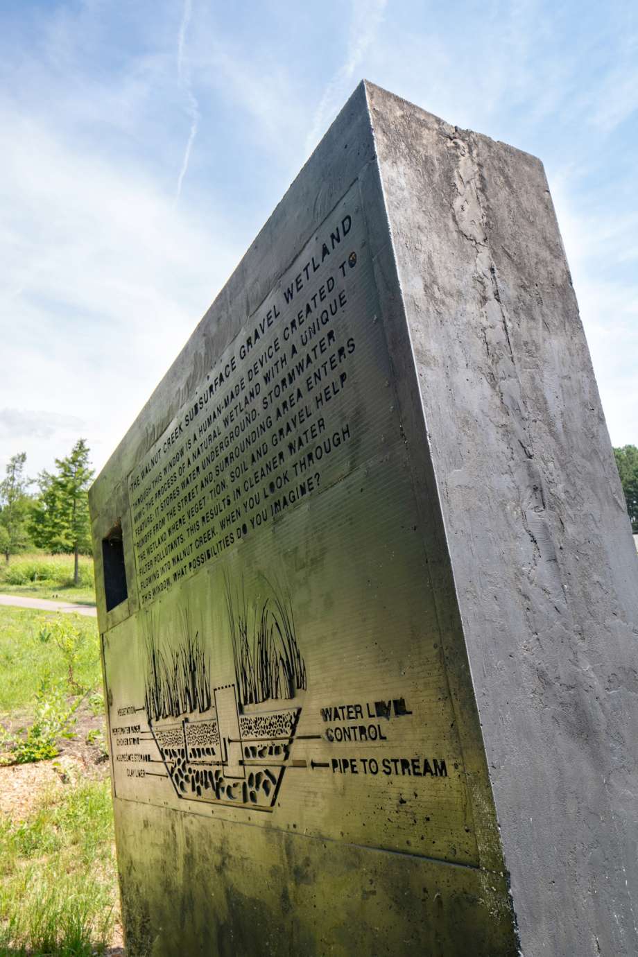 Image of a large concrete monolith sculpture with information about stormwater infrastructure printed on it.