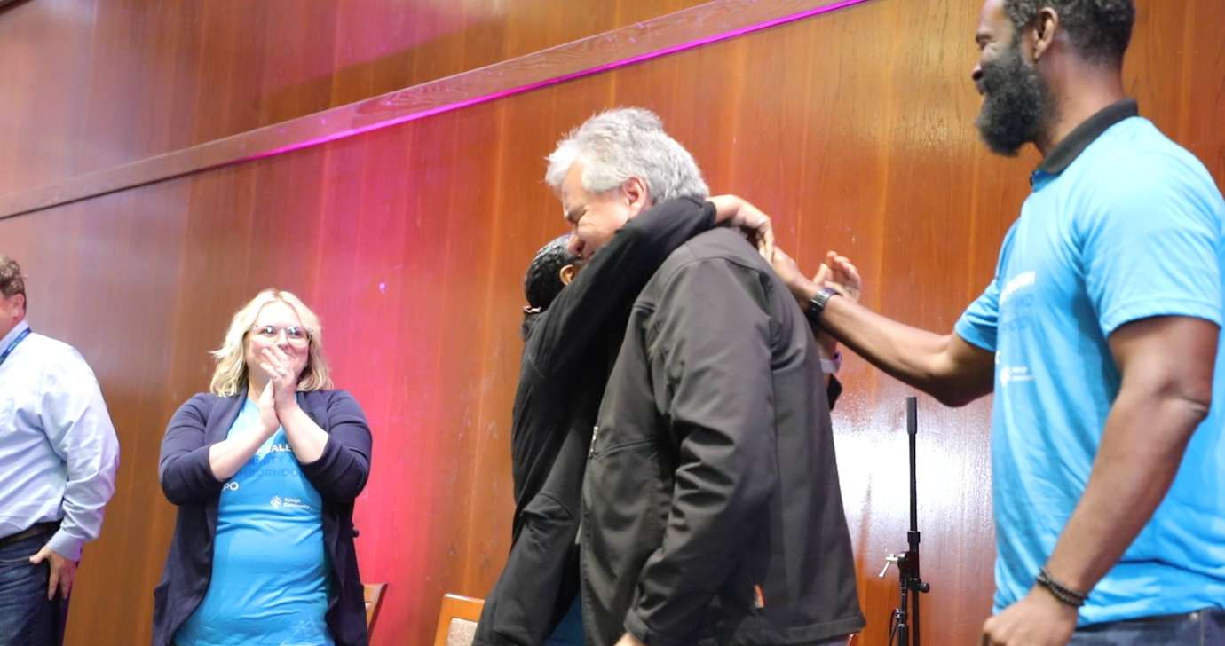 Housing and Neighborhoods staff hug Luis as he is honored for his 20 years of service