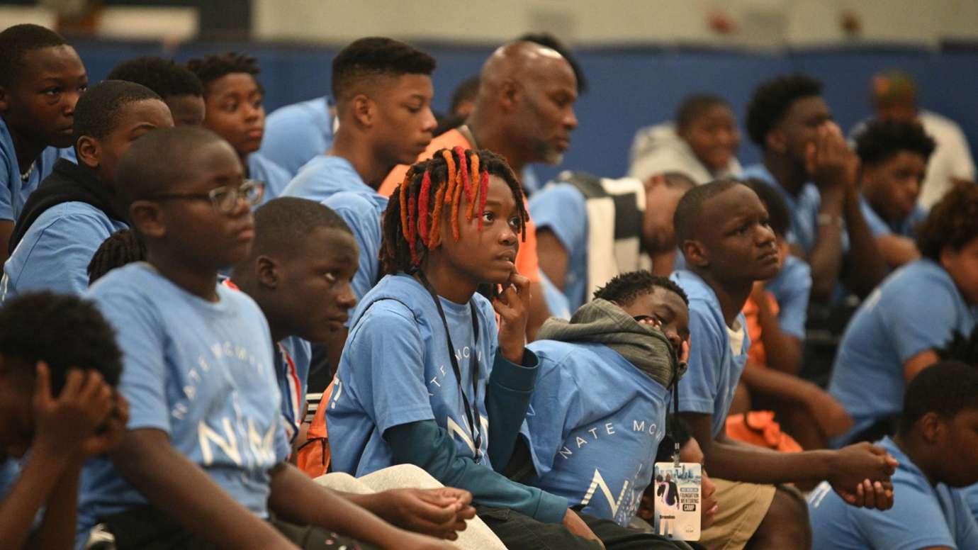 Campers sit and listen instead a gymnasium.