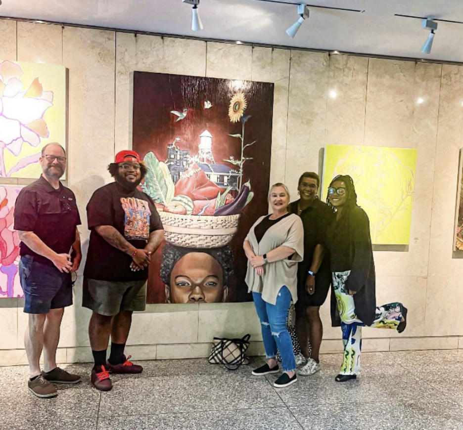 Members of the Human Relations Commission smiling for photo next to large painting indoors