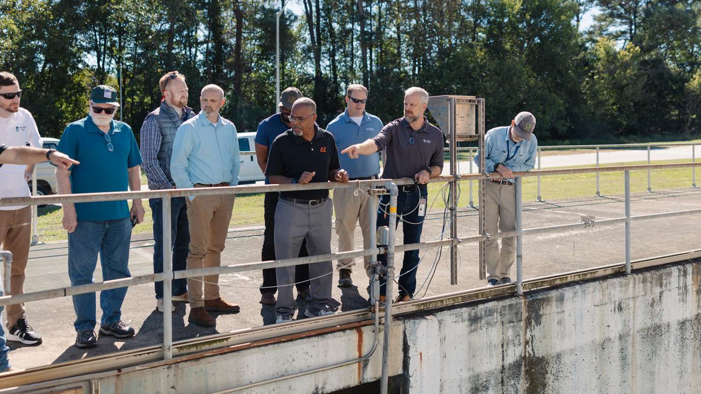 Man talking to tour group outside the facility.