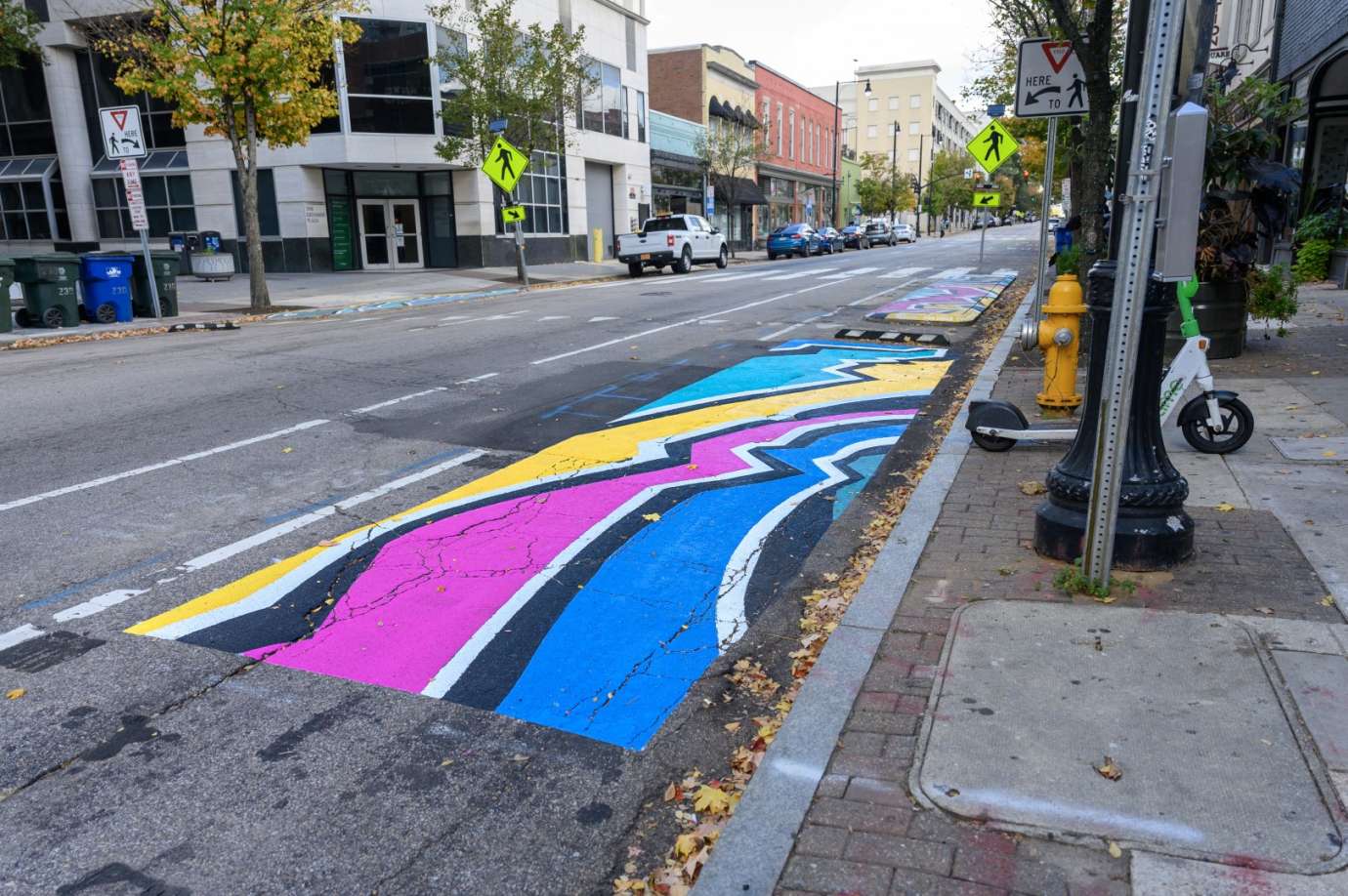 Brightly colored geographic mural painted on raised concrete in a downtown city street. 