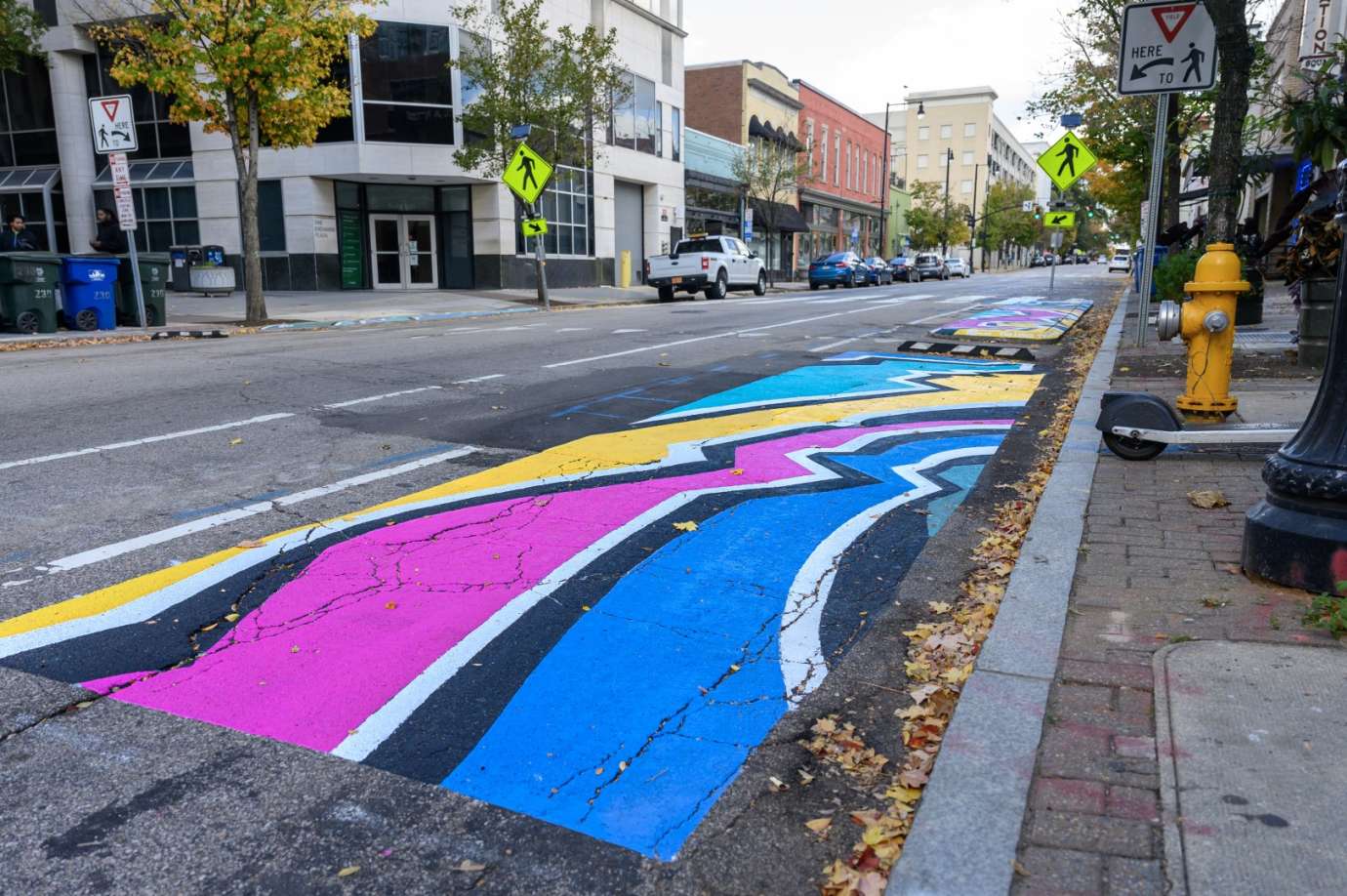 Brightly colored geographic mural painted on raised concrete in a downtown city street. 