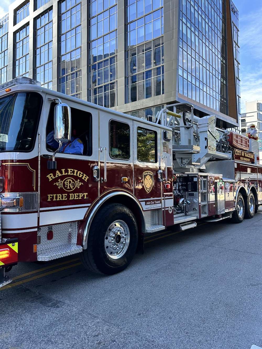 Raleigh fire truck in parade - skyscrapers are visible in background.