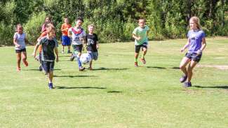 Diverse group of kids playing soccer in open field