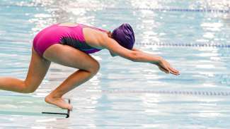 girl in a low mid dive off a spring board at Pullen Park Pool