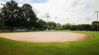 dirt baseball field surround by grass outfield and lights at chavis park