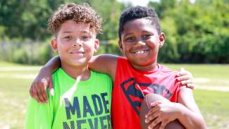 Two young boys with their arms around each other at a summer camp at Barwell Road