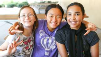 Three young girls with their arms around each other during a program at Marsh Creek Park 