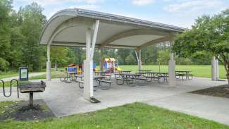 A large outdoor picnic shelter with multiple tables 