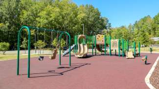 Part of the playground which includes zipline, slides, swings, climbing elements with rubber surfacing.