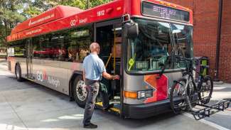 Man boarding bus after bike loaded on bus rack