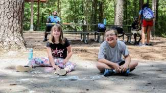 Two kids playing with chalk during a summer camp 