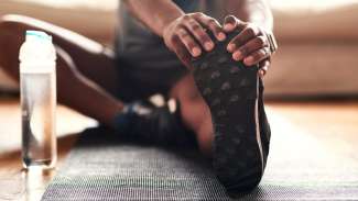 Man stretching to touch foot after working out with bottle of water