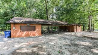 An outdoor picnic shelter with multiple picnic tables and two grills 