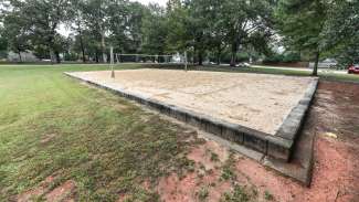 An outdoor sand volleyball court with singular net 