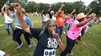 Women dancing in field with hands in the air