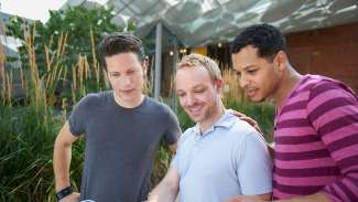 Three individuals reading a pamphlet