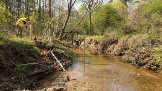 person conducting stream monitoring activities at a creek. 