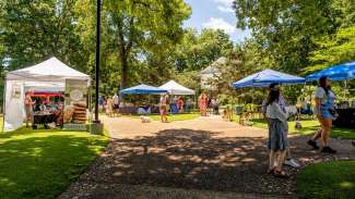 an event with tables, tents and people walking around the park