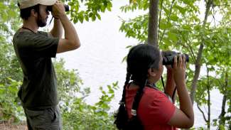 child and adult looking through binoculars outdoors