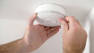 Person's hands installing smoke alarm