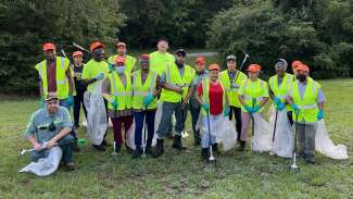 a group of people with safety vests, bags, face masks and litter grabbers