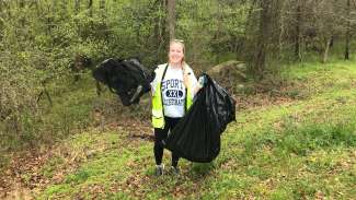 smiling woman with trash bags and safety vest