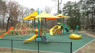 A large playground on a sand surface at Worthdale Park with slides and climbing bars.