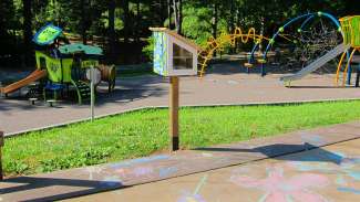 a box on a post filled with chalk sits next to pavement covered in mural and chalk art