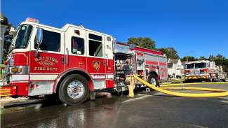 Fire engine 21 parked outside a home with a firefighter detaching the hose from the truck