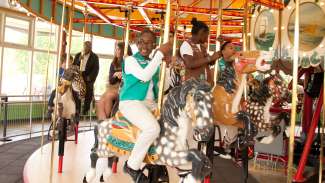 Little girl riding John Chavis Memorial Park historic carousel